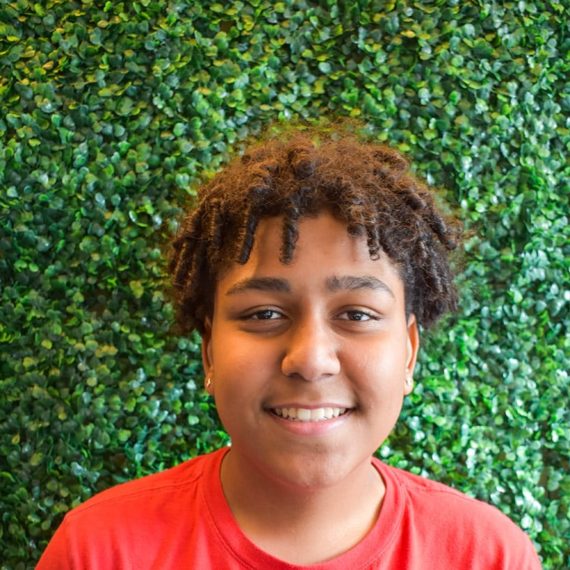 Alex smiling at the camera in a bright red t-shirt.