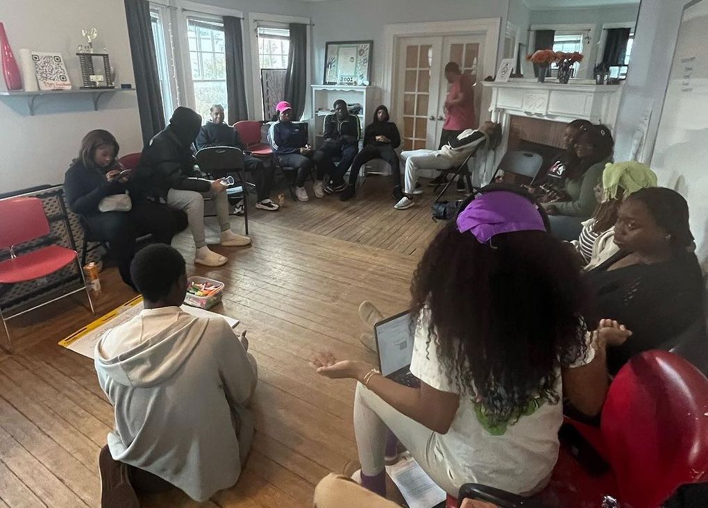 Group of about a dozen youth sitting inside in a circle